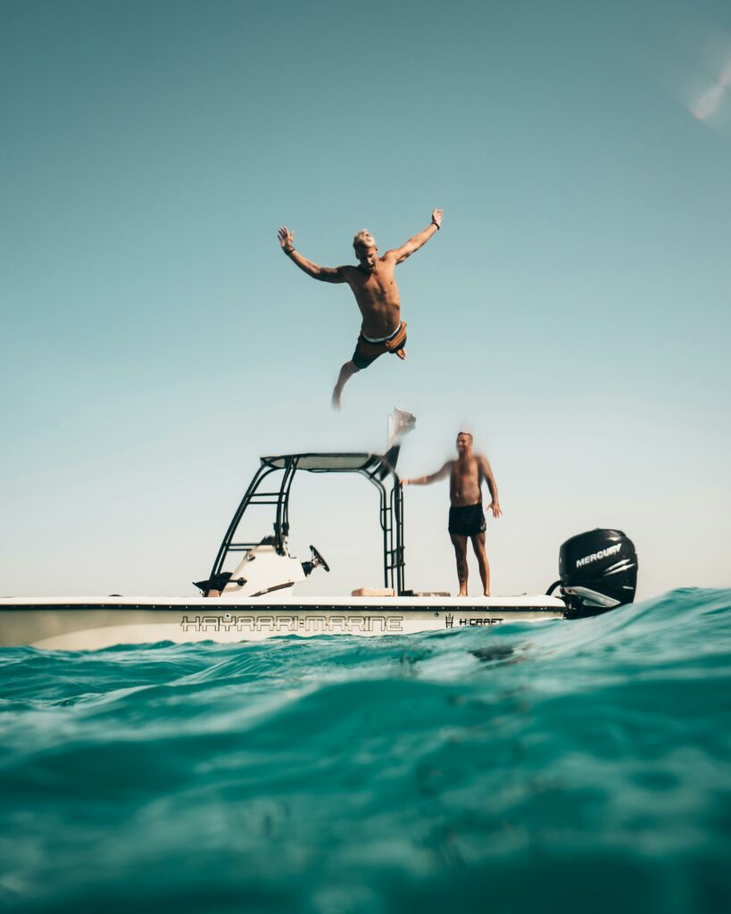 pexels-photo-1122462-1122462 Two men enjoy a sunny adventure, jumping into the Abu Dhabi sea from a boat.