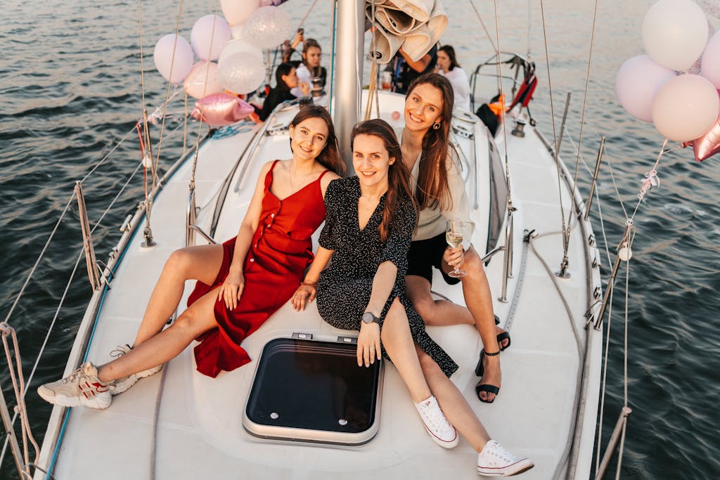 Photo par Maksim Goncharenok Three women celebrate on a yacht at sunset, enjoying a cheerful and memorable time.